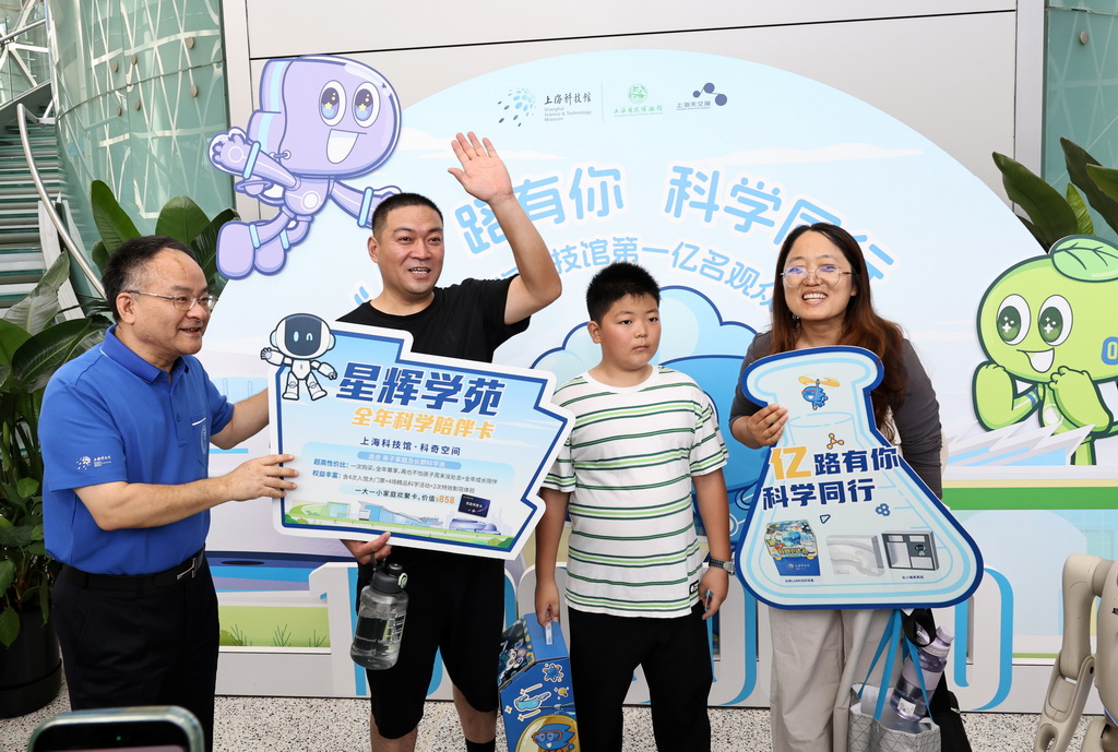 8月18日，上海科技馆馆长倪闽景（左一）为来自山东省滨州市的张志恒小朋友和爸爸妈妈送上第一亿名观众纪念品。