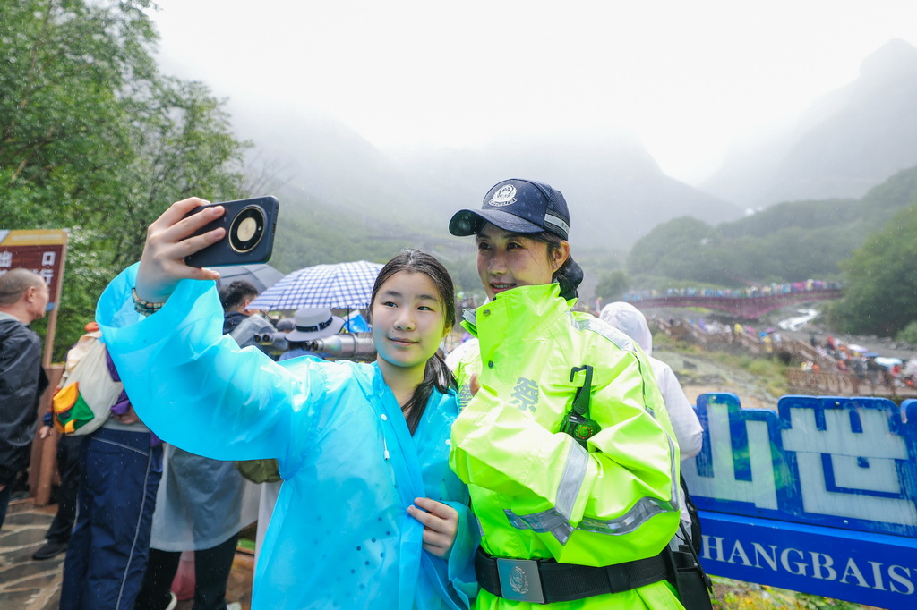 “冰凌花”女子警务队队长王紫涵在长白山北景区与一名游客合影留念（8月18日摄）。