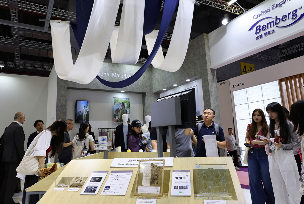 8月25日，参观者在一个展示纺织原材料和自然降解效果的展示台前驻足观看。