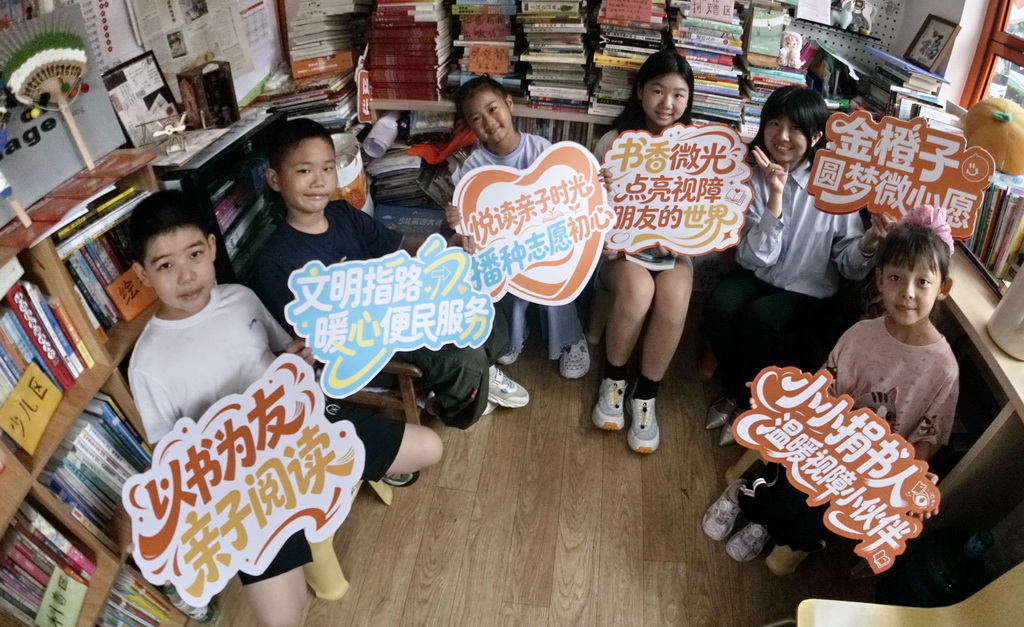 8月25日，小志愿者在金橙子众享驿站内展示志愿服务标语牌。