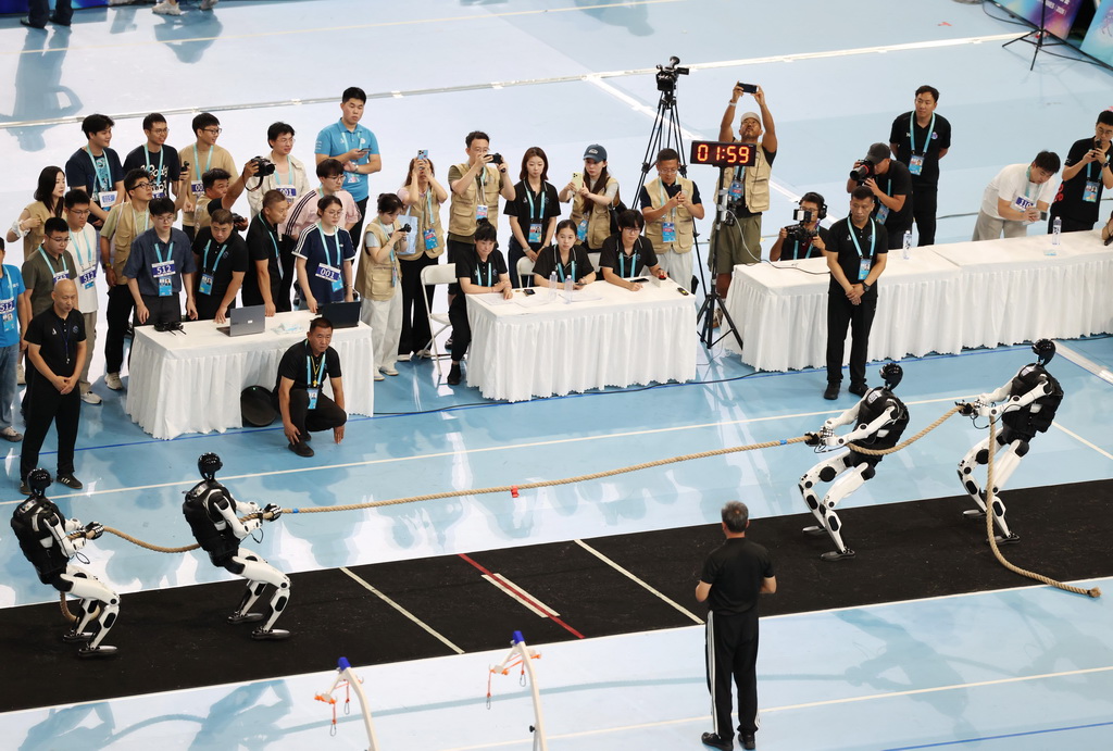 8月25日，天工队的人形机器人（右）在拔河项目重量级比赛中对阵北京人形-华科联队的人形机器人。最终，天工队获得重量级冠军。新华社记者 张晨霖 摄