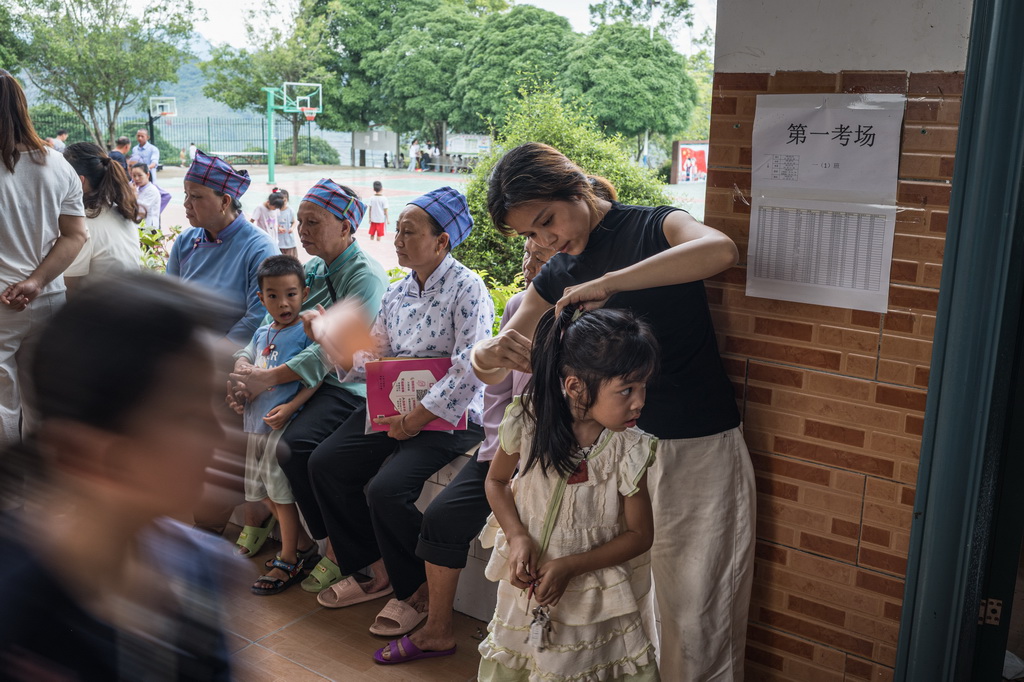 8月30日，在剥隘镇中心学校，家长在学生报到前为学生梳头发。