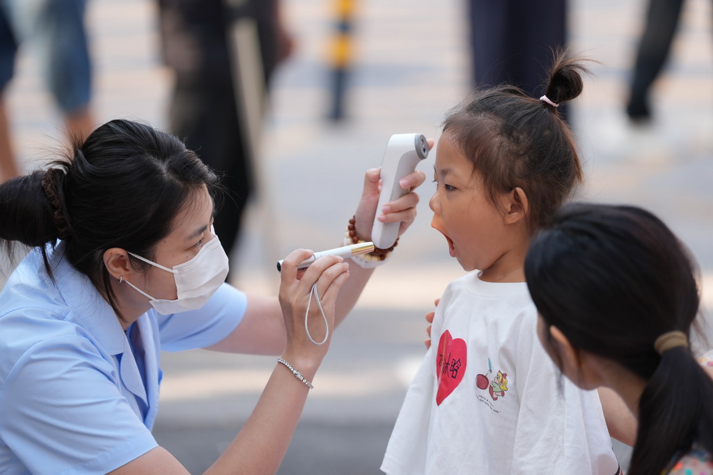 9月2日,北京九龍幼兒園的老師在給孩子做入園晨檢。