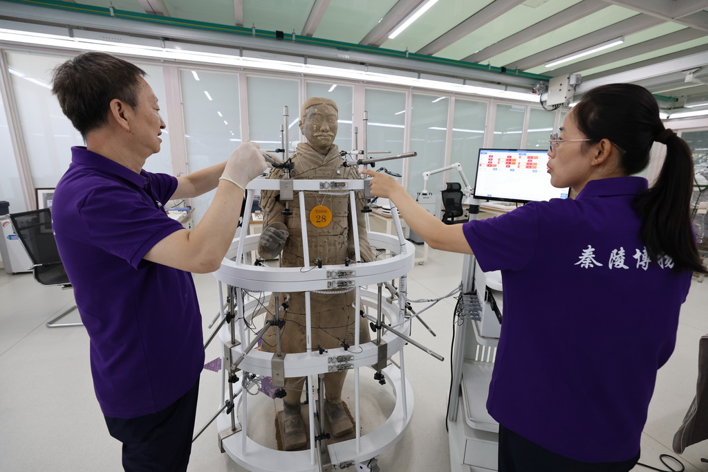 9月3日，秦始皇帝陵博物院研究员兰德省（左）和文物修复师葸艳娥在秦兵马俑一号坑现场保护修复实验室调试兵马俑专用修复定位传感器。