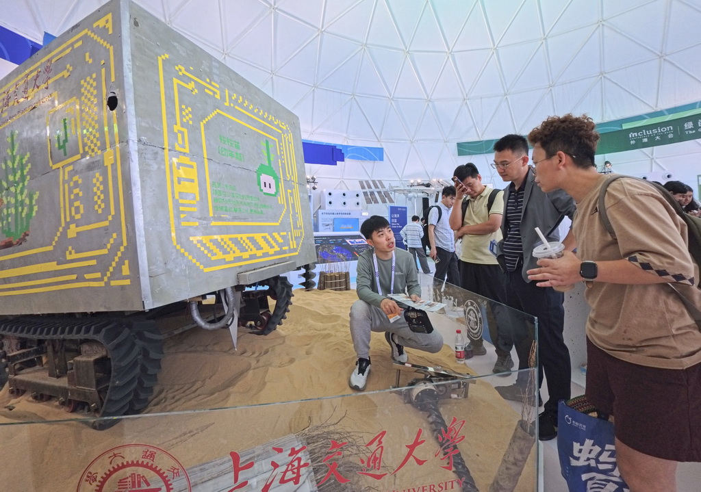 9月10日，工作人员（左一）在向参观者介绍植树治沙机器人展品。