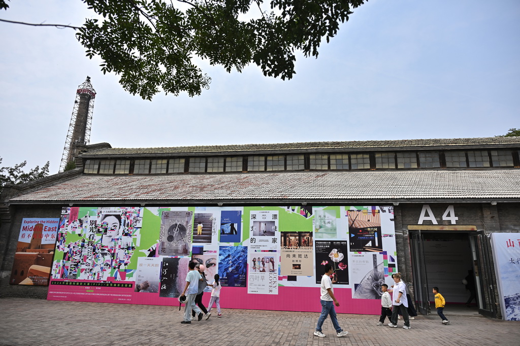 9月19日，参观者在第26届平遥国际摄影大展上参观时经过展馆外的海报。新华社记者 孙瑞博 摄