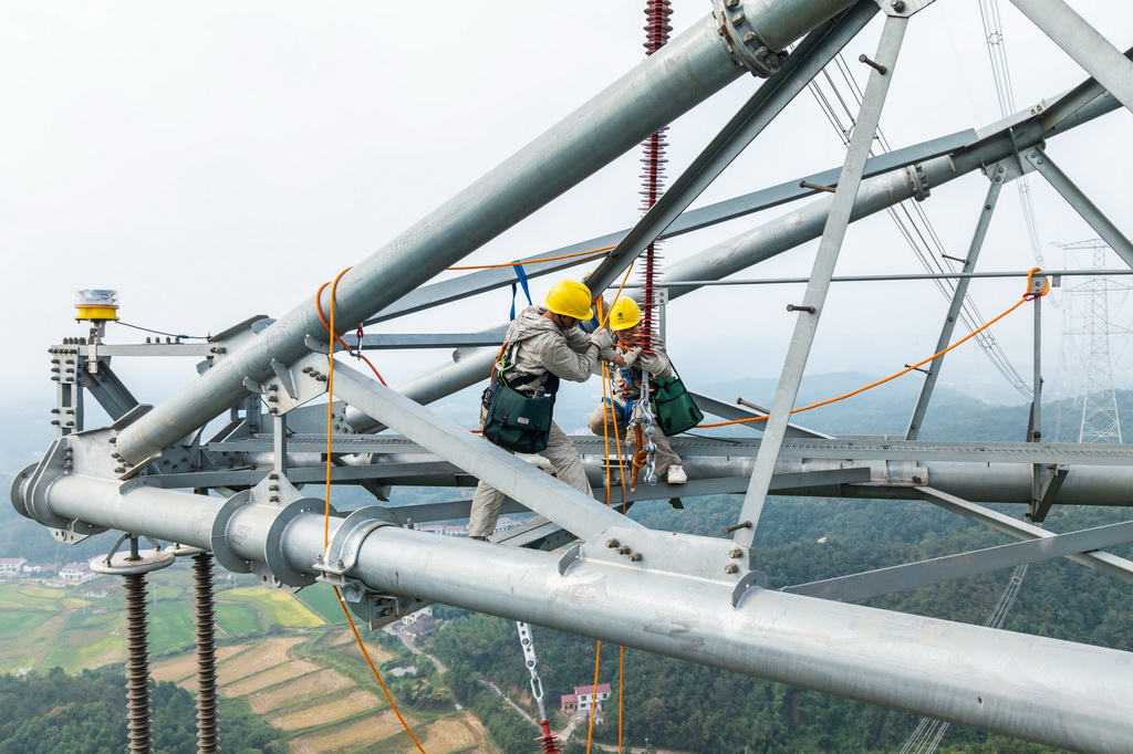 9月20日，在长沙县开慧镇，电力工人在进行防风偏拉索安装作业（无人机照片）。