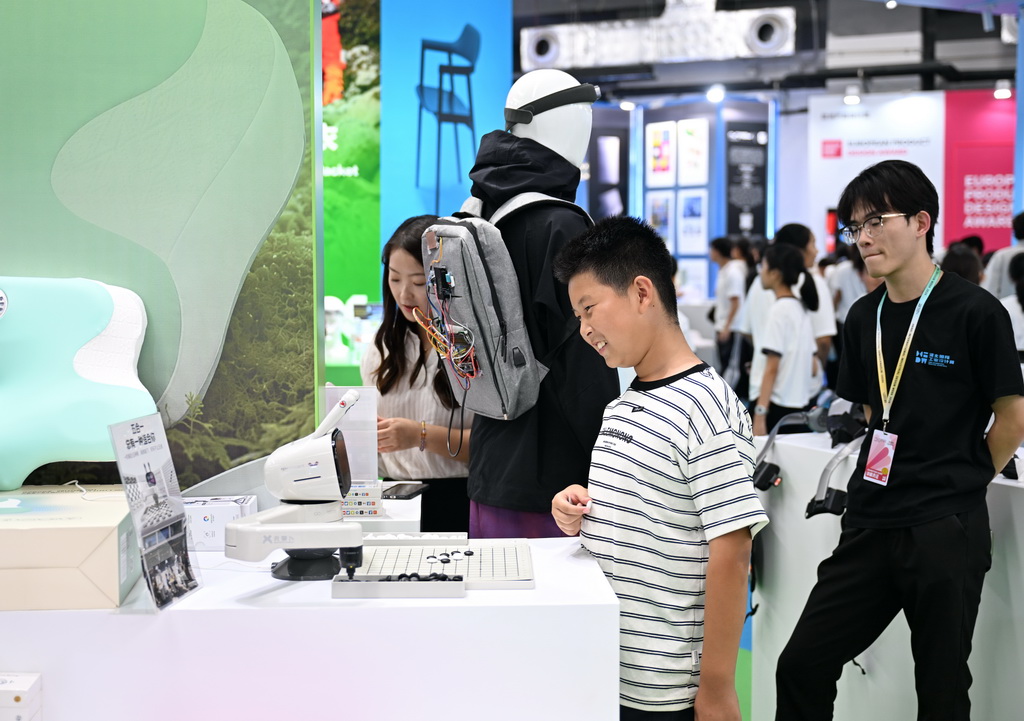 9月21日，学生在河北国际工业设计创新成果展览会现场体验与智能机器人下棋。