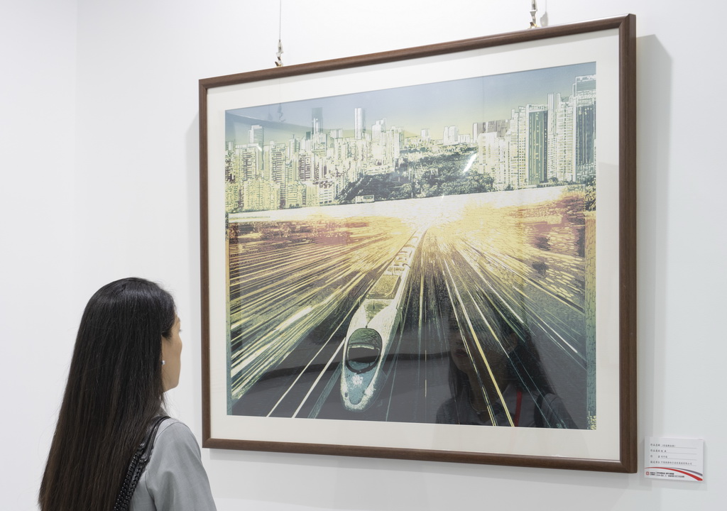 9月29日，在北京中车二七智能制造园，一名观众在观看版画作品《时速新征程》。
