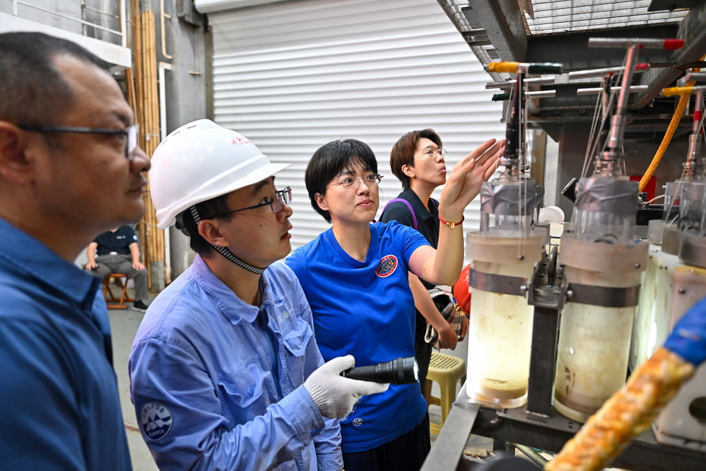 10月10日，潛航員張奕（右二）與“蛟龍”號保障團隊成員商量採樣工具的擺放。