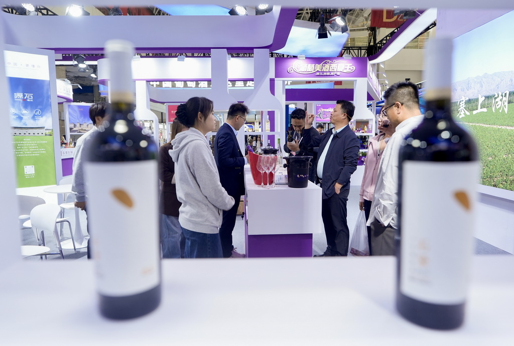 10月13日，观众在博览会上品鉴、了解葡萄酒。