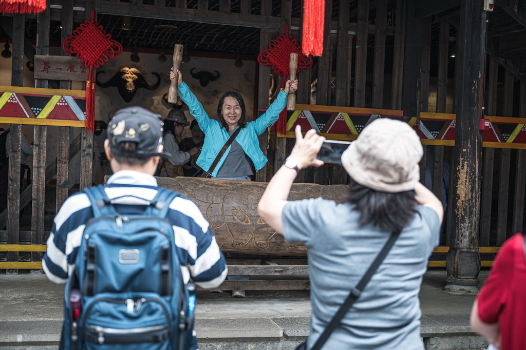 10月19日，游客在腾冲市清水镇三家村中寨司莫拉佤族村体验传统乐器。