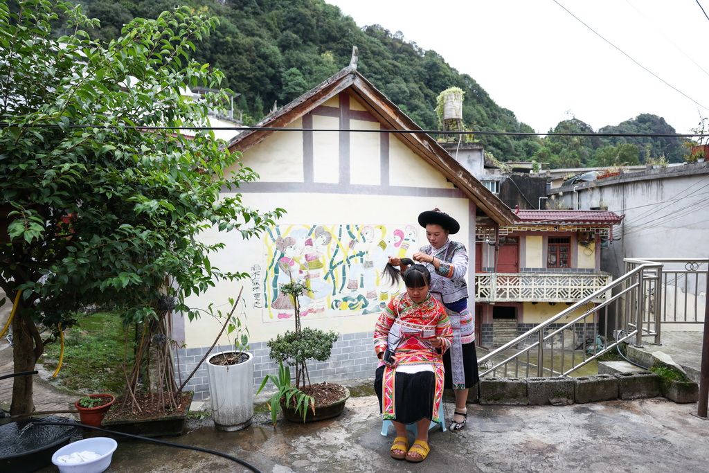 贵州省六盘水市水城区陡箐镇陡箐村的画师罗班妹（后）在给女儿整理头饰（10月5日摄）。