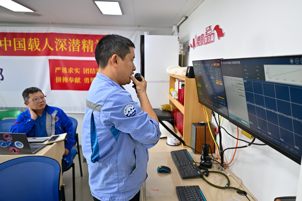 10月10日，“蛟龙”号潜航员齐海滨（右）、程斐在潜器作业监控中心监测“蛟龙”号下潜状态并与下潜作业人员进行沟通。新华社记者 叶昊鸣 摄