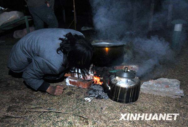 4月14日深夜,青海玉树地震灾区受灾群众在做饭.新华社记者丁林摄