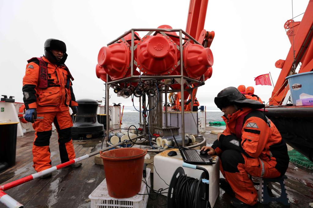 图为刘坤（右）等科考队员和刚回收到船上的海底生物影像观测系统。新华社记者 刘诗平 摄